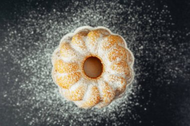 Siyah arkaplanda pudra şekerli kek 