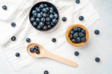 Parlak yaban mersinleri kaselerde sergilenir ve yakınlarda bir tahta kaşıkla sergilenir..