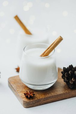 Tarçın çubuklu iki kremalı kış içeceği ve çam kozalaklı ahşap tahta üzerinde anason.