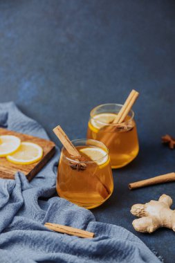 Limon dilimleri, tarçın çubukları, yıldız anason ve zencefilli iki bardak sıcak içecek.