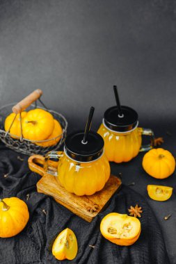 Sonbahar balkabağı içecekleri kavanozlarda pipetler ve baharatlar, karanlık fon, tüm balkabakları