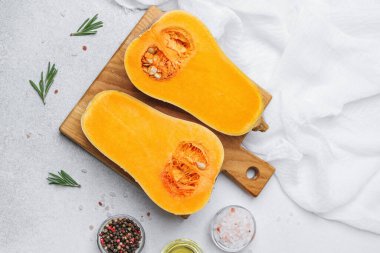 Biberiye ve baharatlarla ahşap tahtada ikiye bölünmüş tereyağlı kabak, sağlıklı yemek malzemesi..