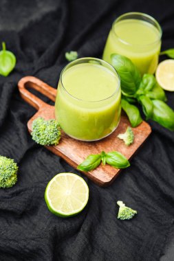 Brokolili yeşil smoothie ve ahşap tahtada limon, taze fesleğen yaprağı, sağlıklı bir içecek.