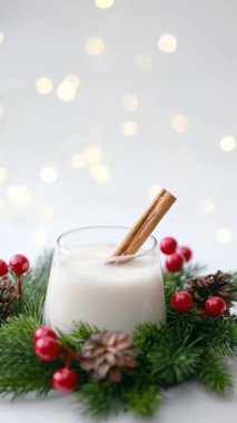 Tarçın çubuğu, çam iğnesi, kırmızı böğürtlen ve yumuşak bokeh lambalı kremalı kış içeceği.