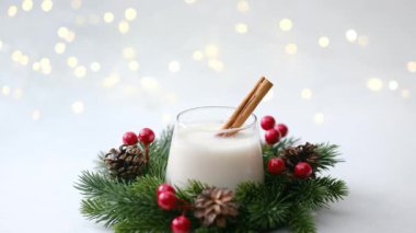 Çam, böğürtlen ve kozalakla çevrili, tarçın çubuklu kremalı bayram içeceği..