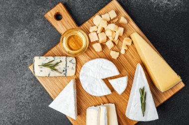 Various cheeses arranged on a wooden board with honey and herbs, perfect for sharing.