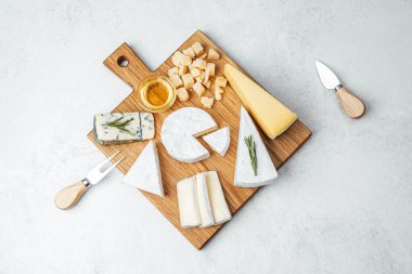 A beautiful arrangement of different cheeses and honey on a wooden serving board.