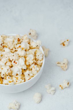 Kabarık, tereyağlı patlamış mısırla dolu bir kase hafif bir yüzeyde oturur..