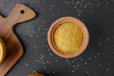 Çatlak buğday, siyah arka plandaki ahşap kasede inliyor. Sağlıklı çiğ tahıl taneleri.