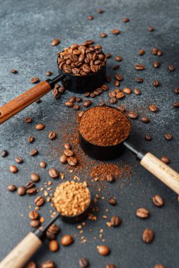 Ground Coffee ve gri arka planda kepçeli fasulyeler.