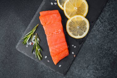 Canlı limon dilimleri ve aromatik otlarla kaplı taze somon filetosu..