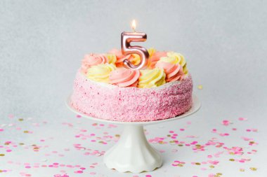 A five-year-old birthday cake adorned with colorful frosting and confetti on the table.