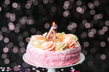 Girdaplarla süslenmiş hoş pembe bir pasta ve dört numaralı mum doğum gününü kutlar..