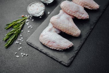 Siyah tahtada çiğ tavuk kanadı ve baharat.
