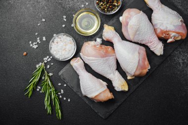 Siyah tahta üzerine yerleştirilmiş tavuk budu, otlar ve tuzlu.