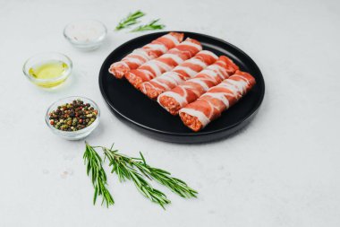 Domuz pastırması siyah tabakta baharat ve biberiye ile sarılmış.