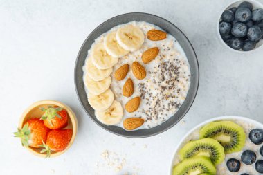 Sağlıklı yulaf ezmesi kasesi, yanında muz bademi ve chia çekirdeği.