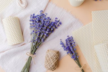 Lavanta buketi, balmumu mumları ve şeftali rengi kumaş arkaplan malzemeleri.