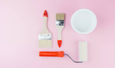 DIY ve iç yenileme konsepti için pembe arka planda rulo, fırça ve kova ile boya seti
