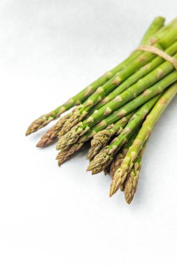 Beyaz arka planda dinlenen yeşil kuşkonmaz mızrakları..