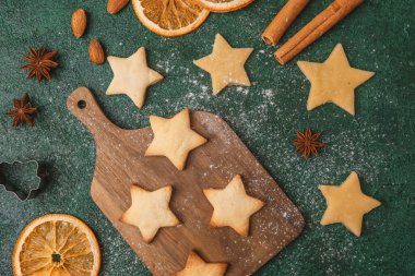 Noel yıldızı kurabiye hamuru ve portakallar şenlikli pişirme ve mevsimlik konsept için yeşil arka planda