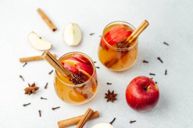 Autumn warm drink with apples, cinnamon sticks, star anise and cloves on light background