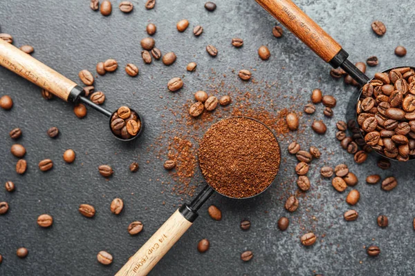 Koyu arka plandaki kepçeleri ölçmek için öğütülmüş kahve ve fasulye.