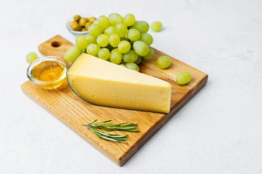 Tahtada peynir, yeşil üzüm, bal ve taze bitkiler birlikte sergilenir..