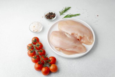 Tuz, biber, biberiye ve kiraz domatesli çiğ tavuk göğsü.