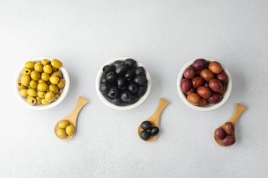 Kase içinde yeşil, siyah ve kalamata zeytinler ve ahşap kaşıklar.