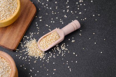 Koyu arkaplanda kinoa tohumlarıyla dolu ahşap kepçe.