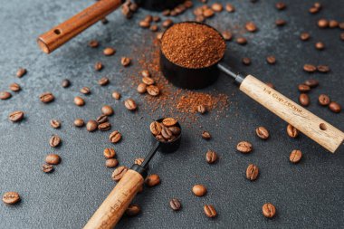 Koyu arka plandaki kepçeleri ölçmek için öğütülmüş kahve ve fasulye.