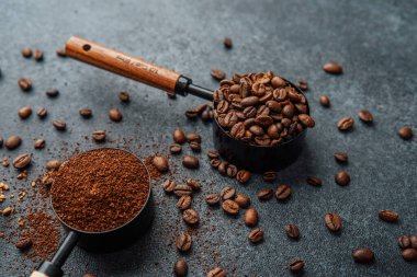 Ground Coffee ve gri arka planda kepçeli fasulyeler.