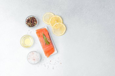 Zeytinyağı, biberiye, baharat ve limon dilimleriyle sergilenmiş somon filetosu..