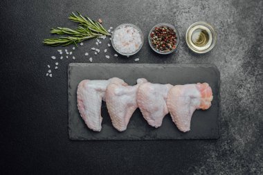 Siyah tahtada çiğ tavuk kanadı ve baharat.