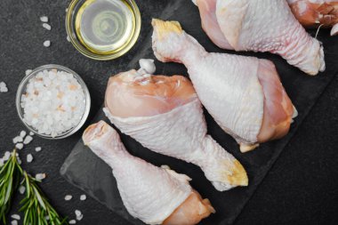 Siyah tahta üzerine yerleştirilmiş tavuk budu, otlar ve tuzlu.