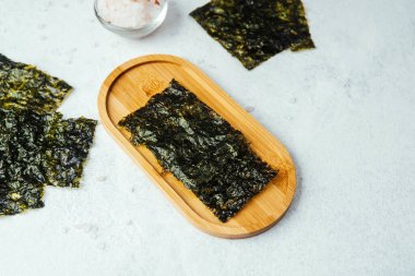 Beyaz arka planda bir kase tuzlu kavrulmuş yosun atıştırmalığı