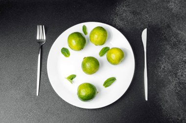 Limonlar yanında nane yaprakları ve çatal bıçaklarla bir tabakta sergilenir..