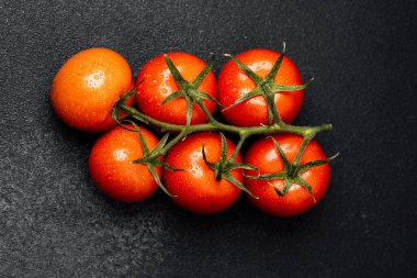 Olgun kırmızı domatesler yeni toplanır ve koyu bir arkaplanda sıralanır..