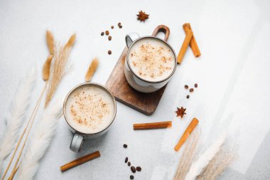 İki bardak sıcak, tarçınlı kahve ve arka planda yıldız anason.