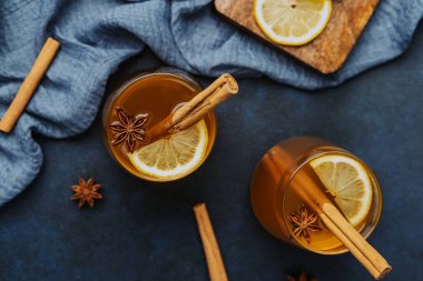 Tarçın çubukları, limon dilimleri ve karanlık yüzeyde yıldız anasonu olan ılık bir içecek.