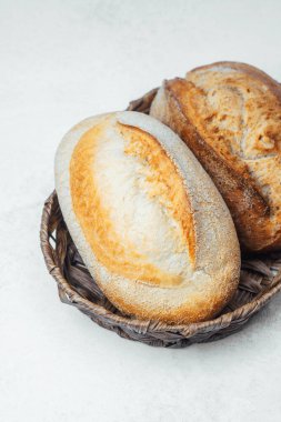 İki altın kabuklu ekmek, dokuma sepetinde birbirine sokulur..