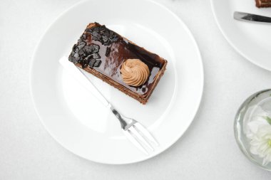 Lezzetli bir çikolatalı pasta dilimi. Beyaz bir tabakta çatalla krema ve gevrek parçalar.