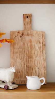 Rafta seramik krema ve koyun heykelciği olan tahta kesme tahtası.