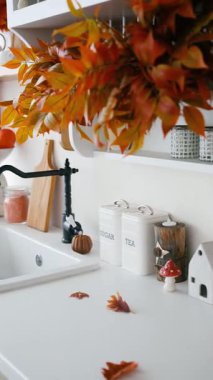 Mutfak tezgahında şeker ve çay kutularıyla sonbahar yaprakları ve balkabağı.