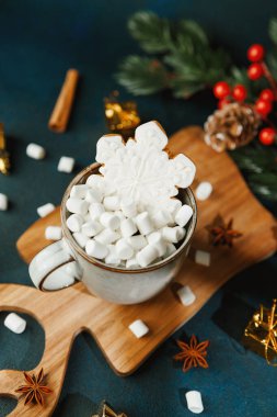 Tahta tahtada, üzerinde lokum ve kar tanesi kurabiyesi olan sıcak kakao kupası ve kış süslemeleri.