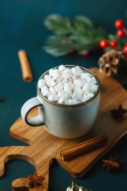 Tahta bir tahtanın üzerinde kremalı ve tarçınlı sıcak kakao içeceği, şenlikli bir arka plan.