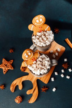 Zencefilli adam kurabiyeleri içi marşmelov ve sıcak çikolatayla dolu bardakların üzerinde otururlar..