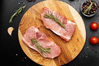 Domuz pirzolası, taze biberiye filizleriyle ahşap bir kesme tahtasının üzerinde sergilenir..