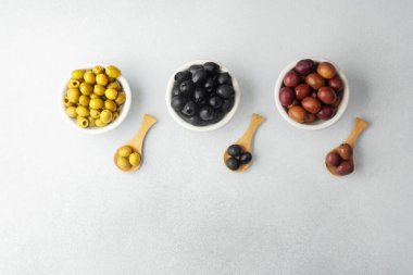 Kase içinde yeşil, siyah ve kalamata zeytinler ve ahşap kaşıklar.